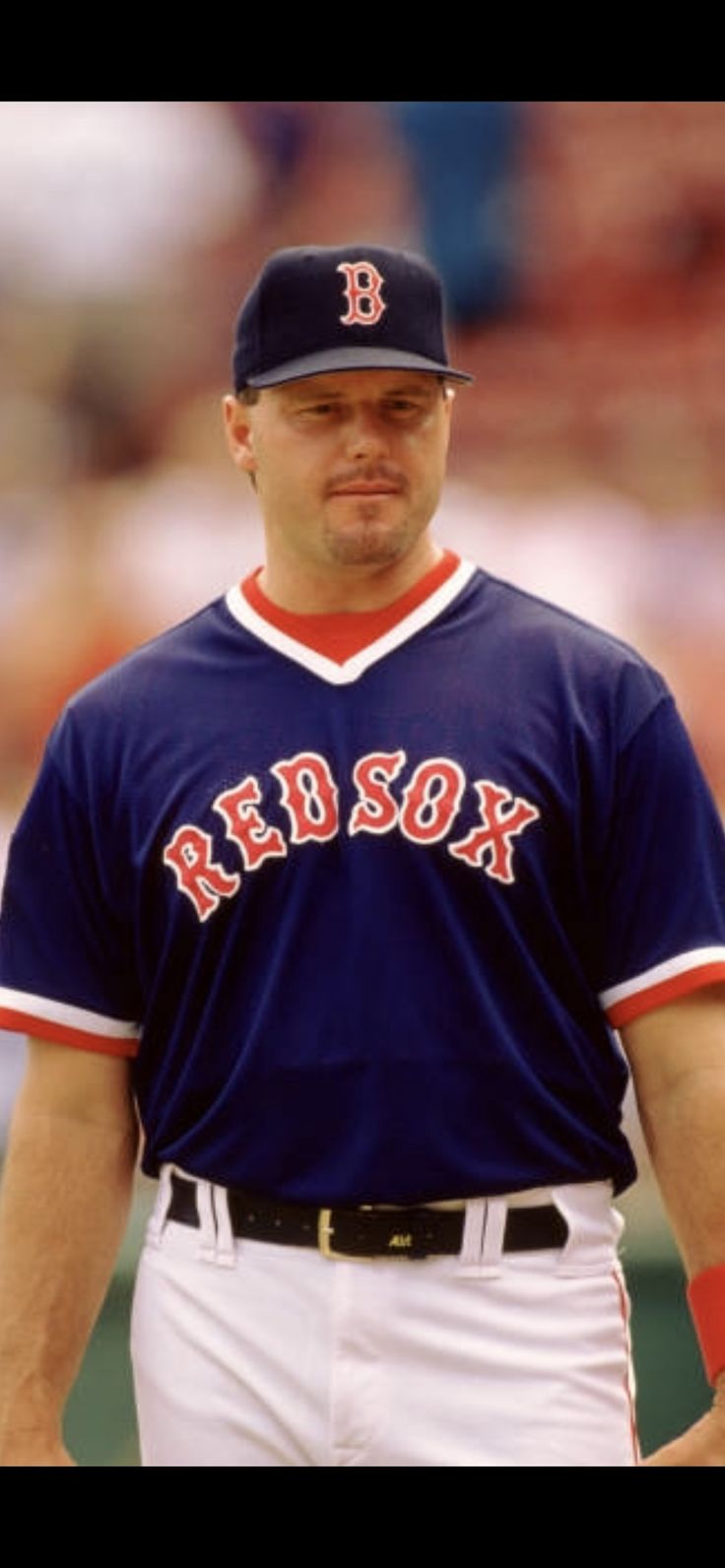 a baseball player is standing in the outfield with his hands on his hips and wearing a red sox uniform