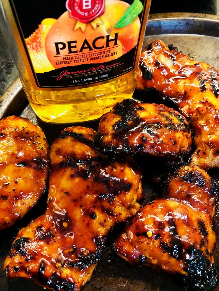 chicken wings with bbq sauce on the side and bottle of peach barbecue sauce in the background