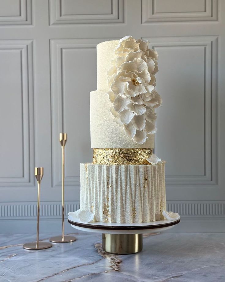 a white and gold wedding cake sitting on top of a table