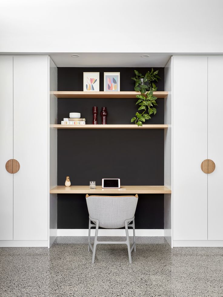 a desk and chair in a room with black walls, white cupboards and shelves