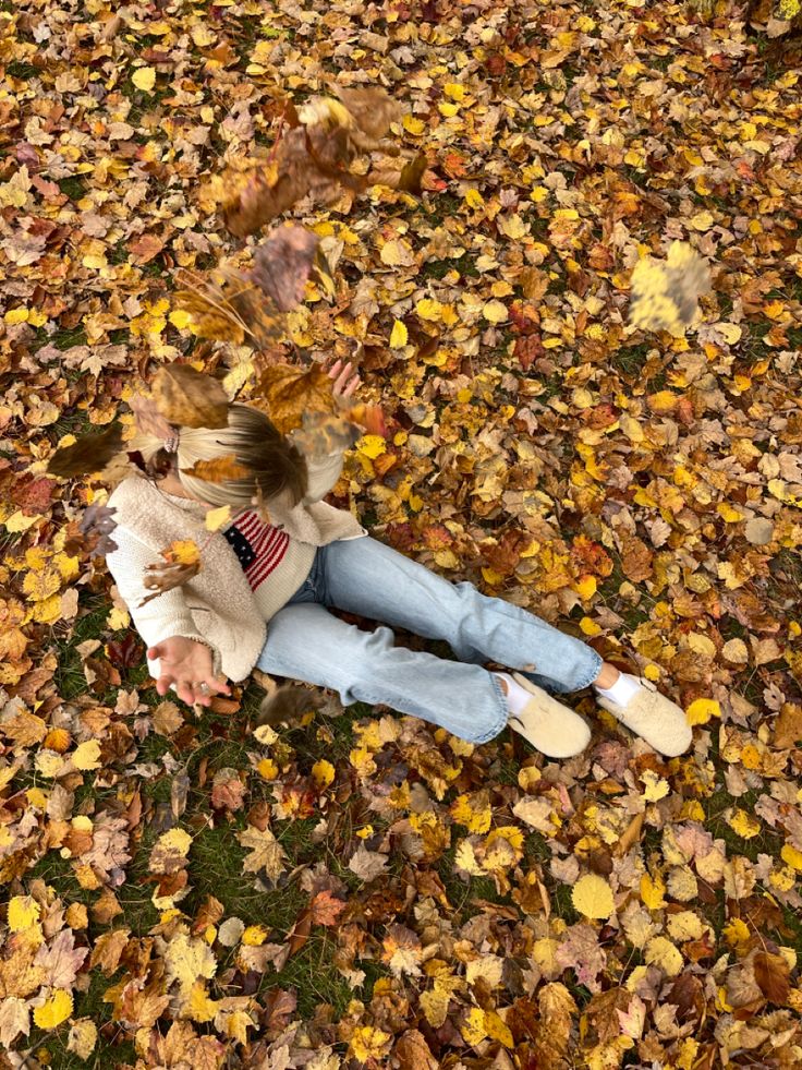 a woman laying on the ground covered in leaves