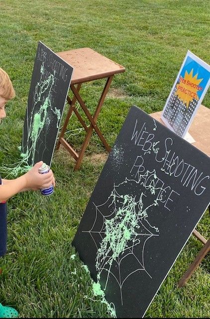 a little boy sitting in the grass next to two chalkboards with writing on them