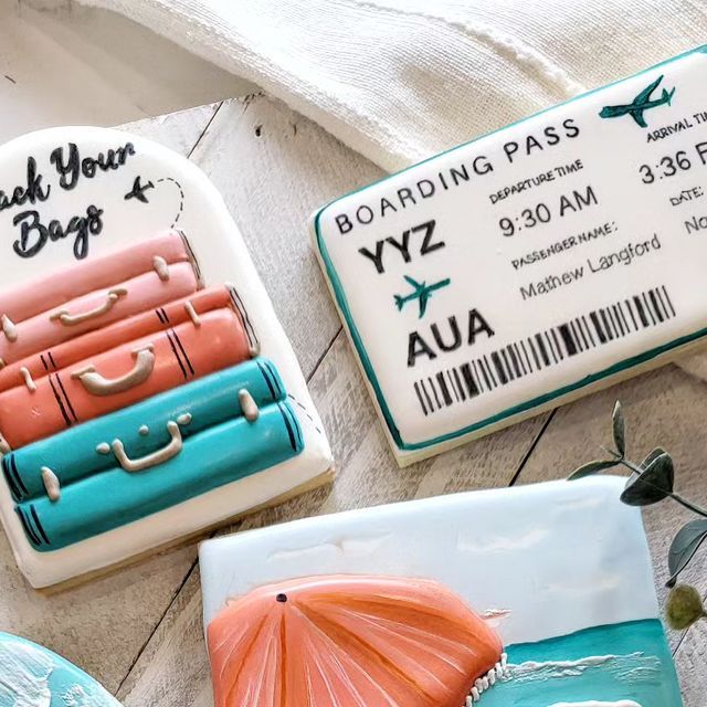 some cookies are decorated with luggage and beach themed decorations, including an air plane ticket