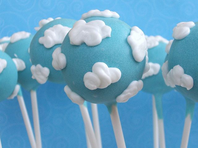 blue cake pops with white frosting and clouds on them are arranged in a row