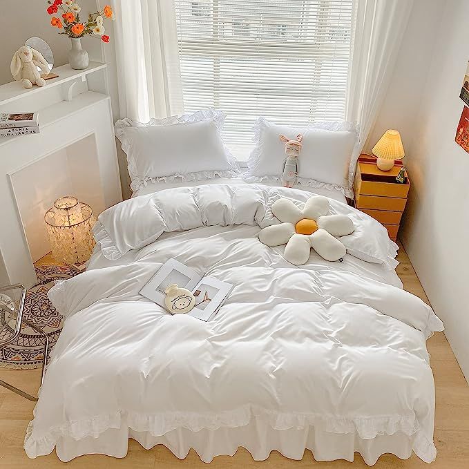 a bed with white sheets and flowers on it in front of a window next to a fireplace