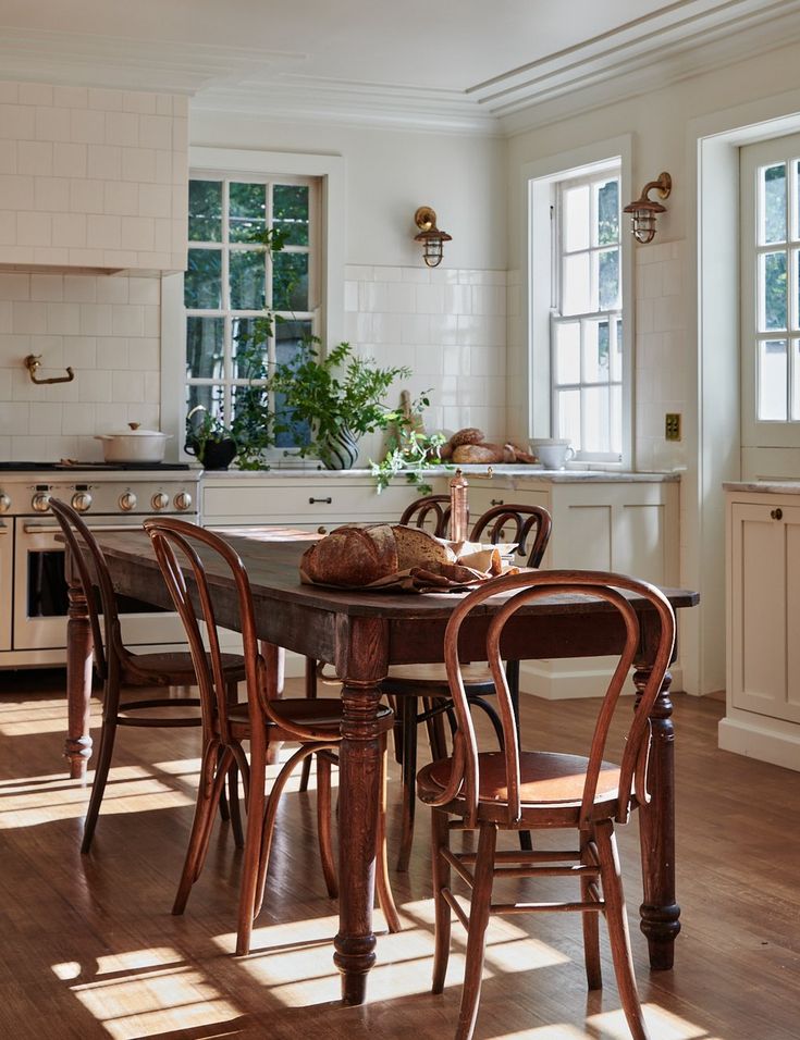 a kitchen table with chairs around it in front of a stove top oven and window