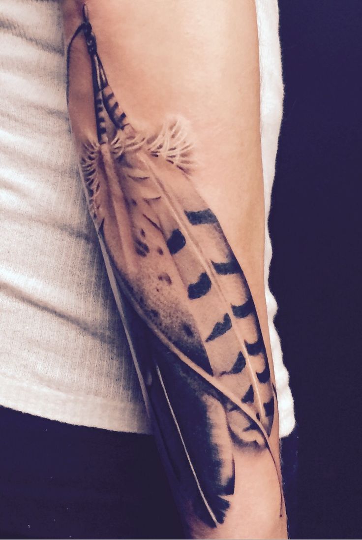 a woman's arm with a feather tattoo on it