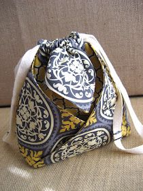 a purse sitting on top of a couch next to a white bag with yellow and blue designs