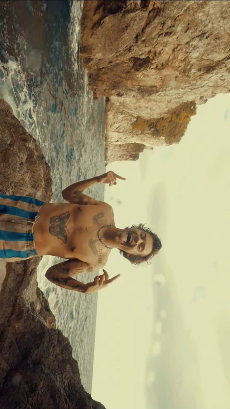 a man standing on top of a cliff next to the ocean