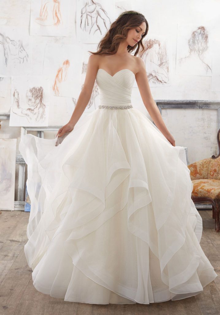 a woman in a white wedding dress is posing for the camera with her hands on her hips