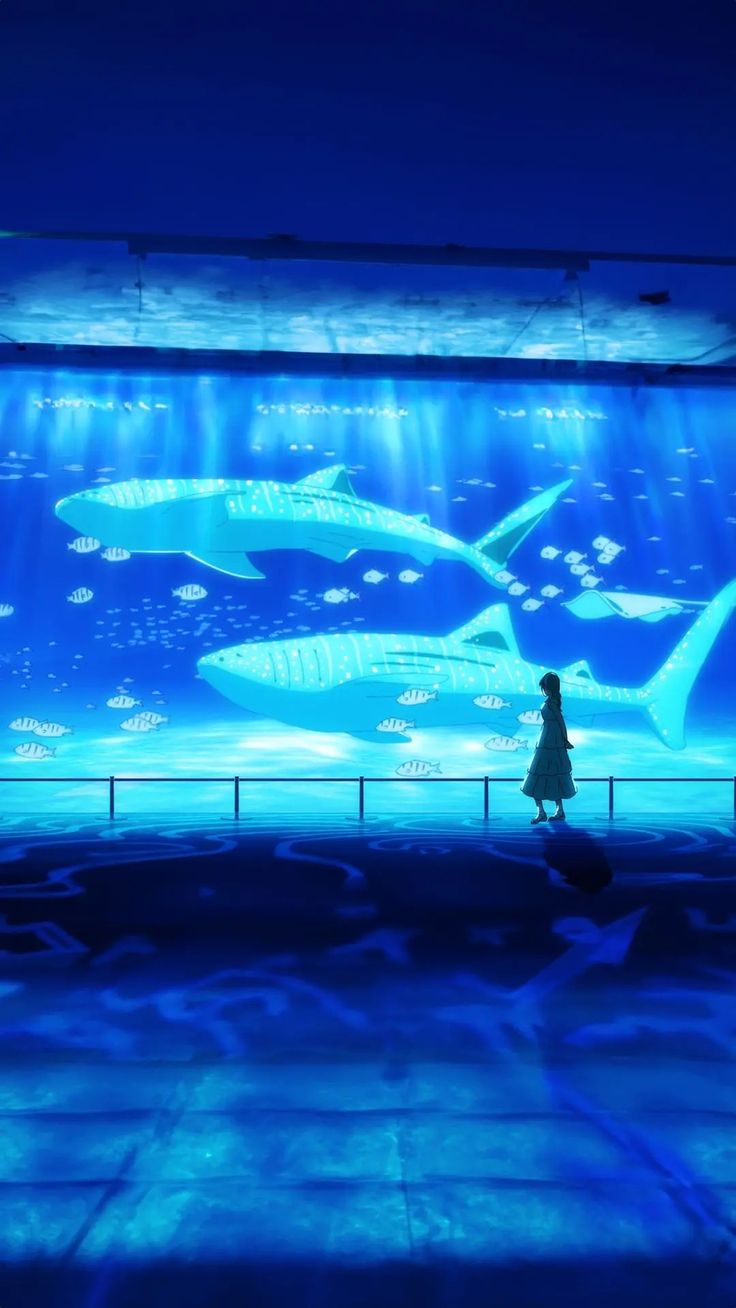 a woman standing in front of a large aquarium