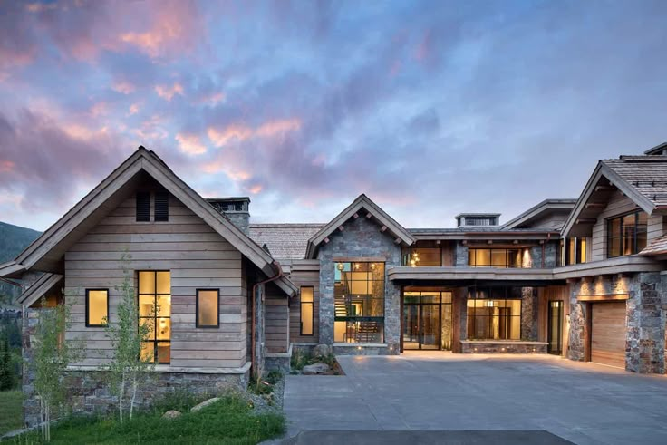 a large house with lots of windows on the front and side of it at dusk