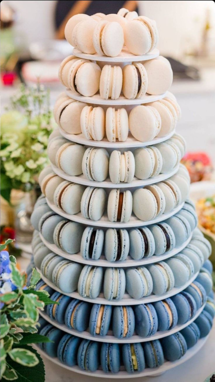 a stack of blue and white macaroons sitting on top of each other in front of flowers