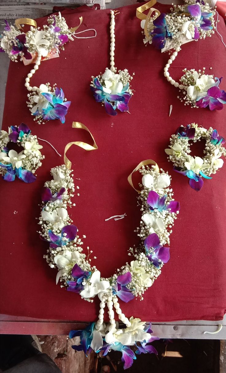 a bunch of flowers that are sitting on a red table cloth with pearls and beads