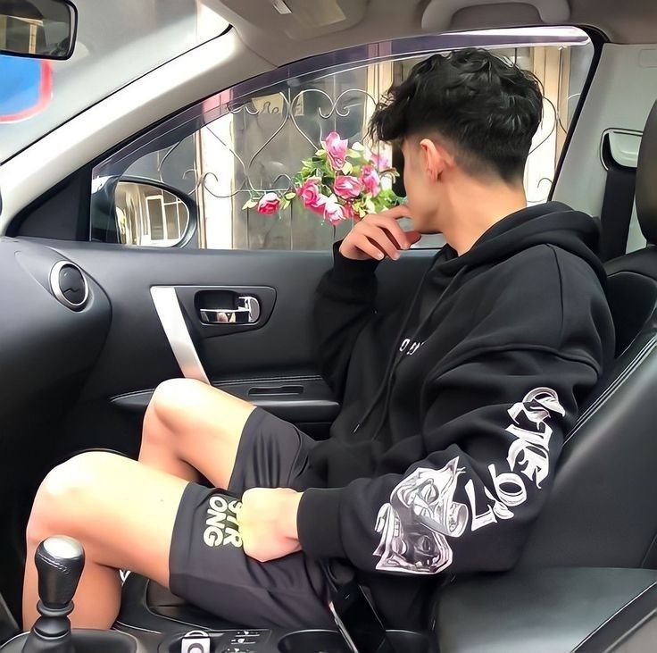 a man sitting in the passenger seat of a car with his feet on the steering wheel