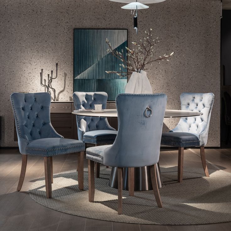 a dining room table with blue chairs and a vase on the centerpiece in front of it