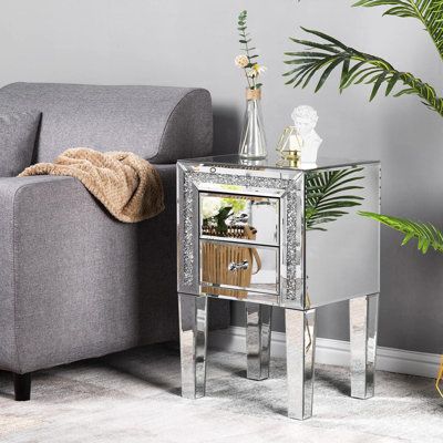 a living room with a couch, chair and mirror side table in the corner next to a potted plant