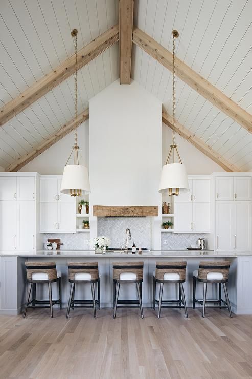 a large kitchen with white cabinets and wooden beams on the ceiling, along with bar stools