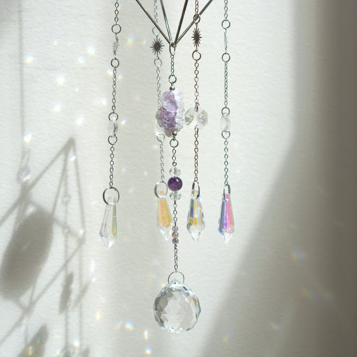 a wind chime hanging from the side of a wall with beads and crystals on it