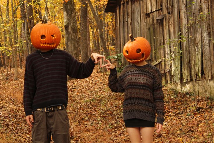 two people wearing pumpkin heads in the woods