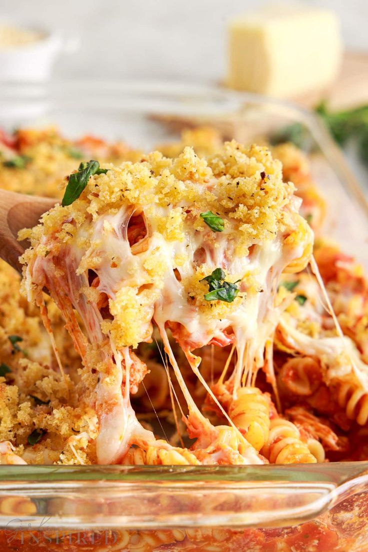 a casserole dish filled with pasta and cheese being lifted from the casserole