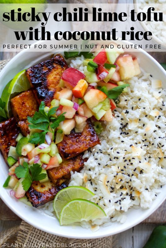 a white bowl filled with rice and fruit next to sliced limes on the side