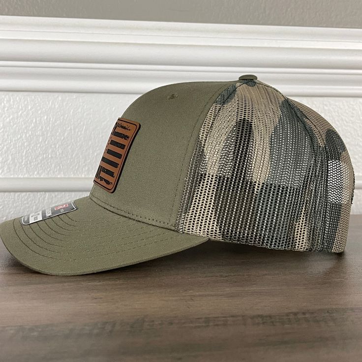 Whiskey Steak Guns & Freedom American Flag Patriotic 2A Leather Patch Hat Green/Camo. Specifications: 🧢 Richardson original 112 trucker; adjustable for the perfect fit 🎩 60/40 cotton/polyester blend for comfort 📏 One size fits most 🏷️ Expertly laser engraved leatherette patch design 📦 Ships in 2 to 3 business days from our Orlando Studio Care Instructions: 🚫 Do not wash; spot clean only Please Note: 🌈 Colors may vary from photos based on your viewing screen. Orlando Studios, Military Camouflage Trucker Hat With Curved Bill, Military Cap With Logo Patch, Military Hat With Adjustable Logo Patch, Adjustable Military Camouflage Snapback Hat, Military Camouflage Trucker Hat One Size, Green Camo, Patch Design, Leather Patches