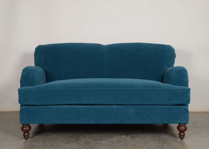 a blue couch sitting on top of a hard wood floor next to a white wall