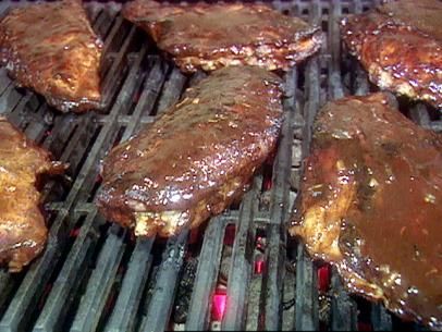 steaks being grilled on the grill with brown gravy and sauce over them