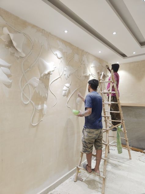 two people are painting the wall with white paint