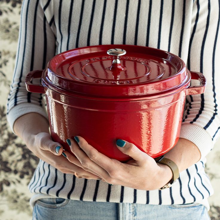 a woman holding a red pot in her hands