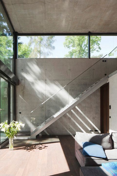 a living room filled with furniture next to a stair case and glass windows on the wall