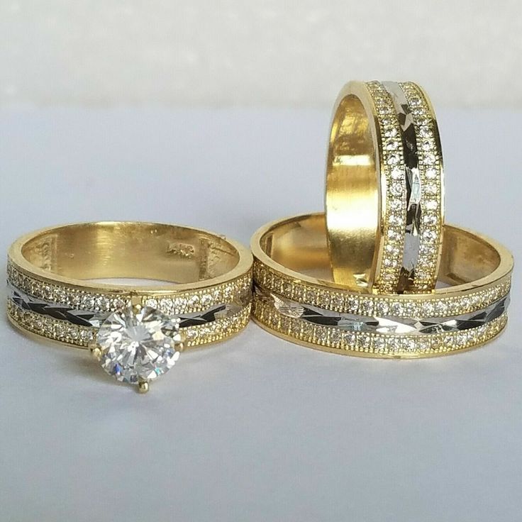 two gold wedding rings with white diamonds on each one and an engagement ring in the middle