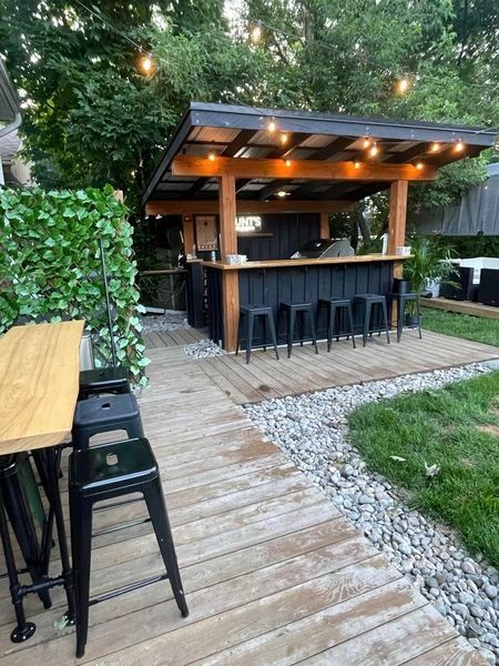 an outdoor bar is set up in the middle of a backyard with lots of greenery