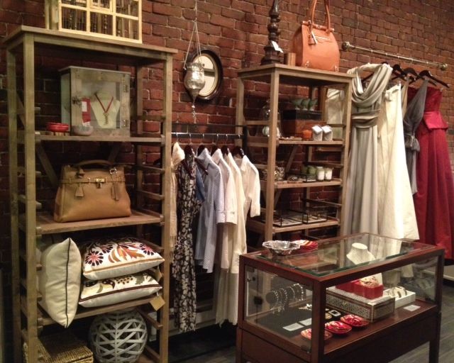 a display case filled with lots of different types of clothing and bags on shelves next to a brick wall