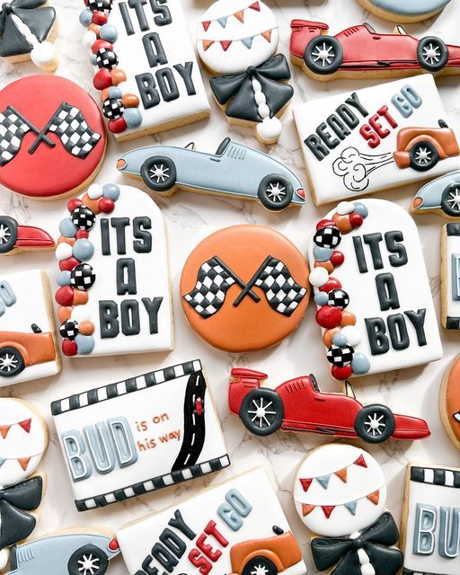 decorated cookies are displayed on a white tablecloth with cars and race flags in the background