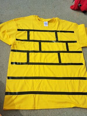 a yellow t - shirt with black lines on the front and back, sitting on concrete