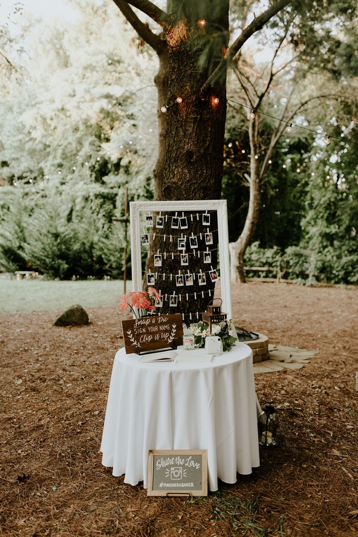 a table that has some pictures on it with lights hanging from the tree in the background