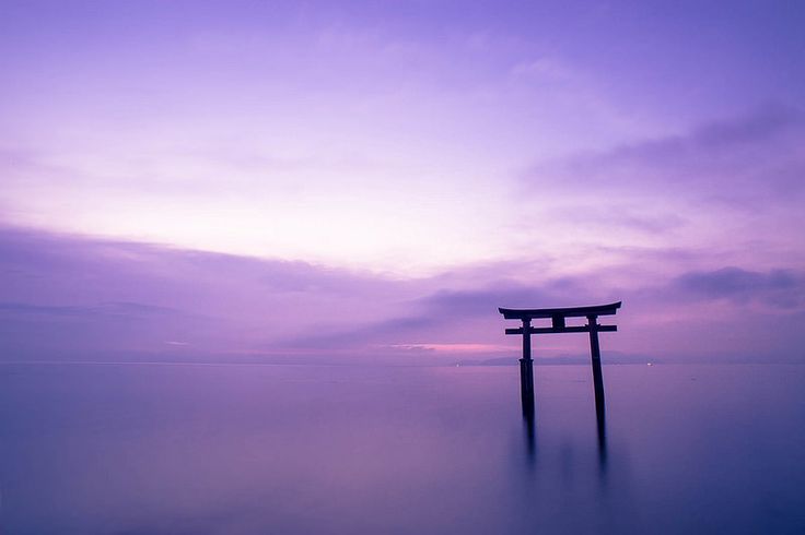 a purple and blue sky over the ocean with a small wooden structure in the foreground