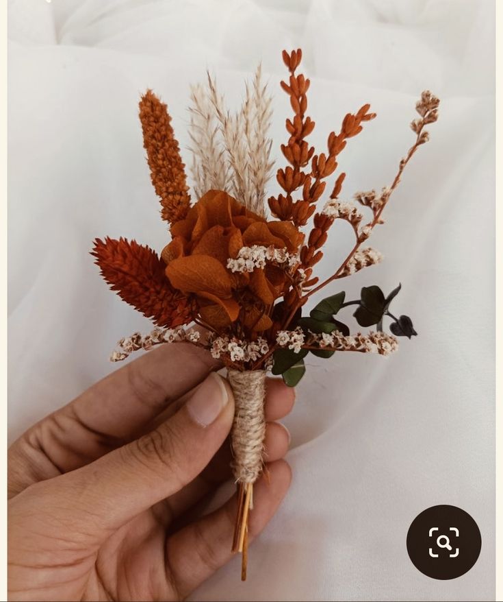 a hand holding a dried flower arrangement in it's palm