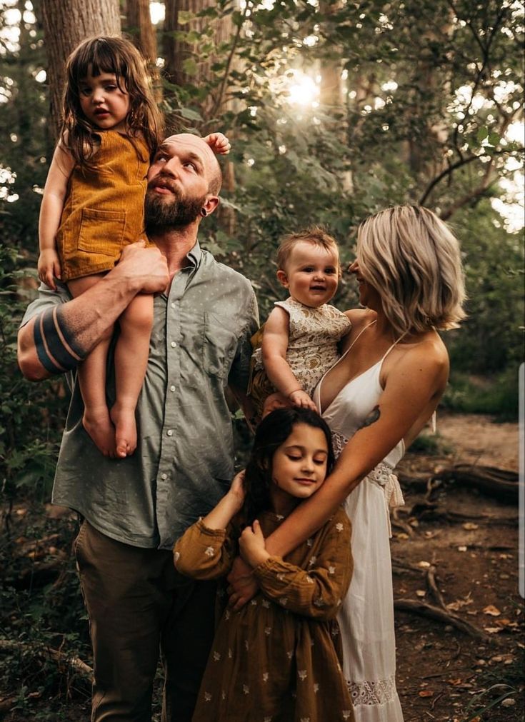 a man and woman holding two children in the woods