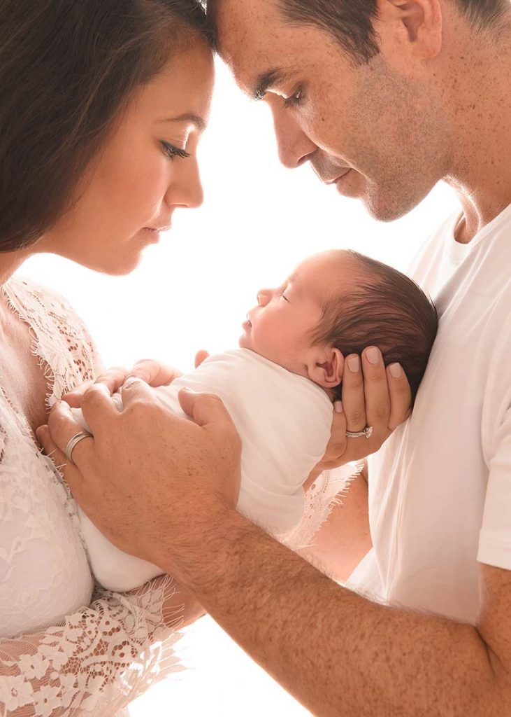 a man and woman holding a baby in their arms