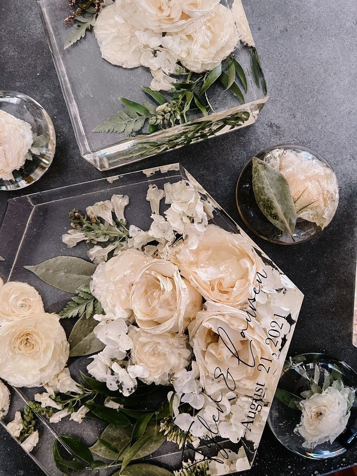 some flowers are sitting on a table next to two glass dishes with candles in them