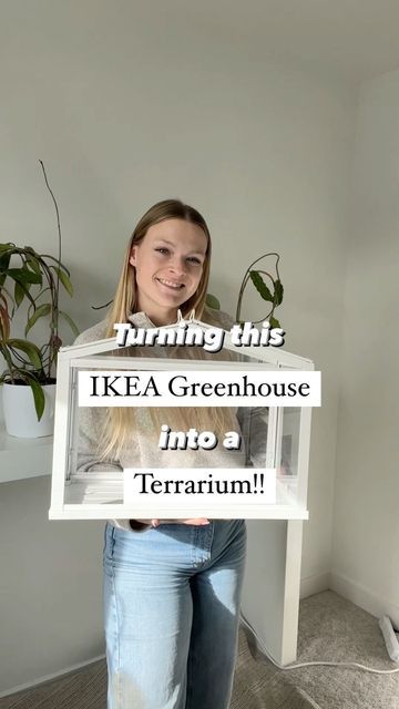 a woman holding up a sign that says, turning this ikea greenhouse into a terrarium