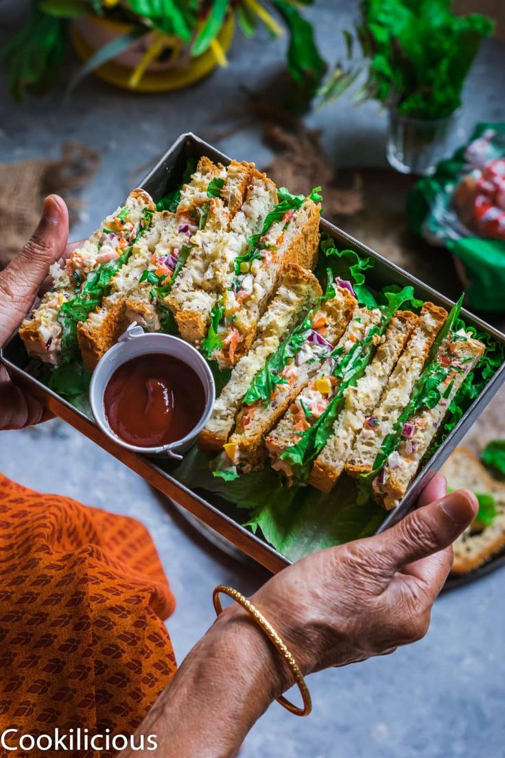 a person holding a tray with food on it and dipping sauce in the other hand