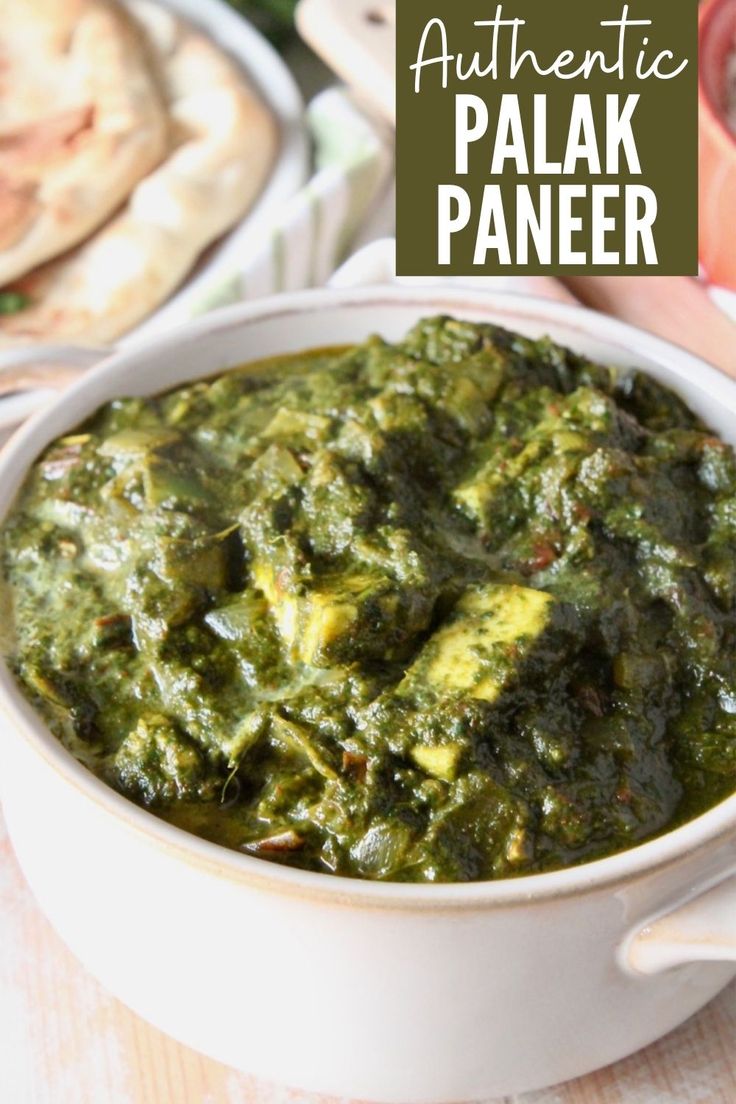 a white bowl filled with spinach and other food on top of a wooden table