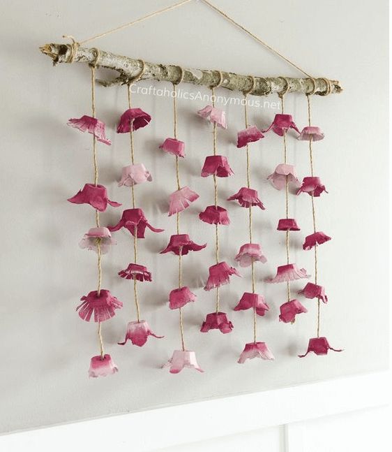 a wall hanging made out of pink paper flowers and birds on the string, with one bird perched on it's head