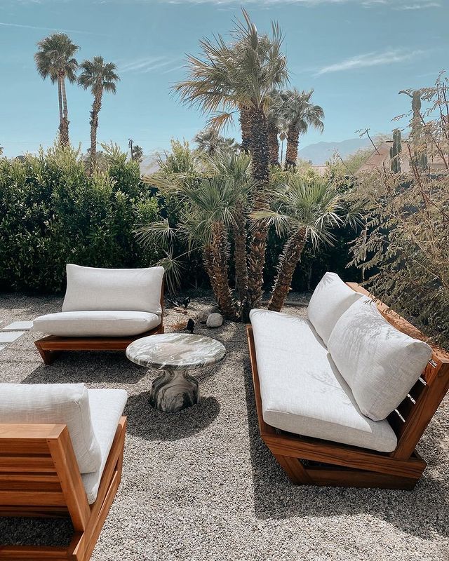 an outdoor seating area with palm trees in the background and white cushions on top of it