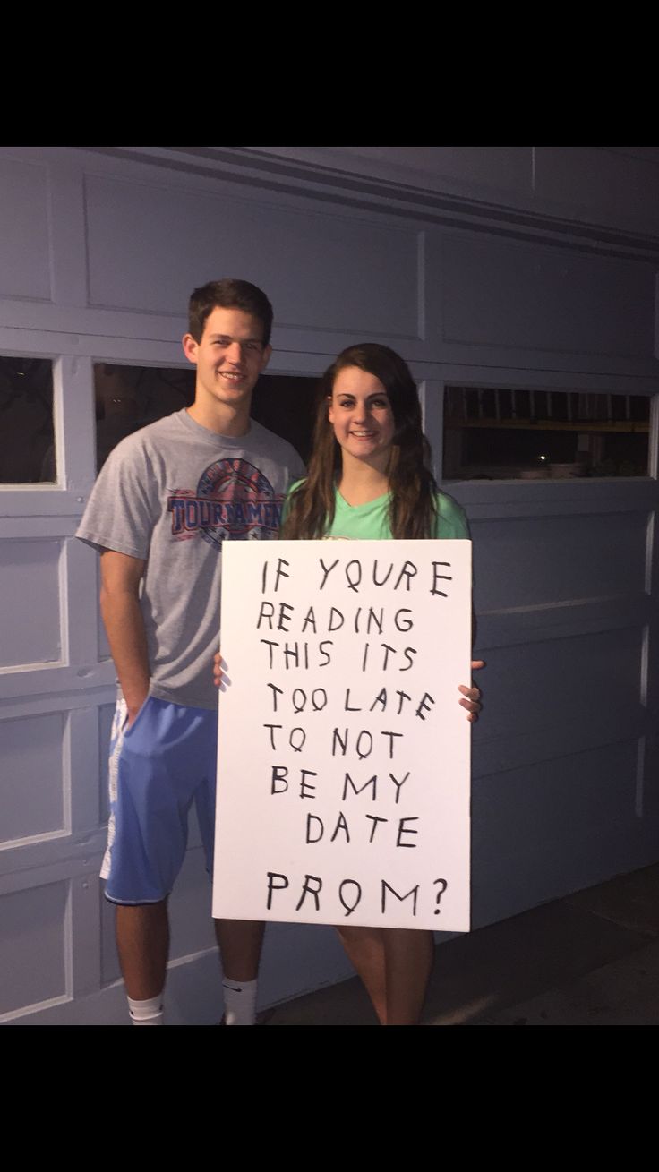 two people standing in front of a garage holding a sign