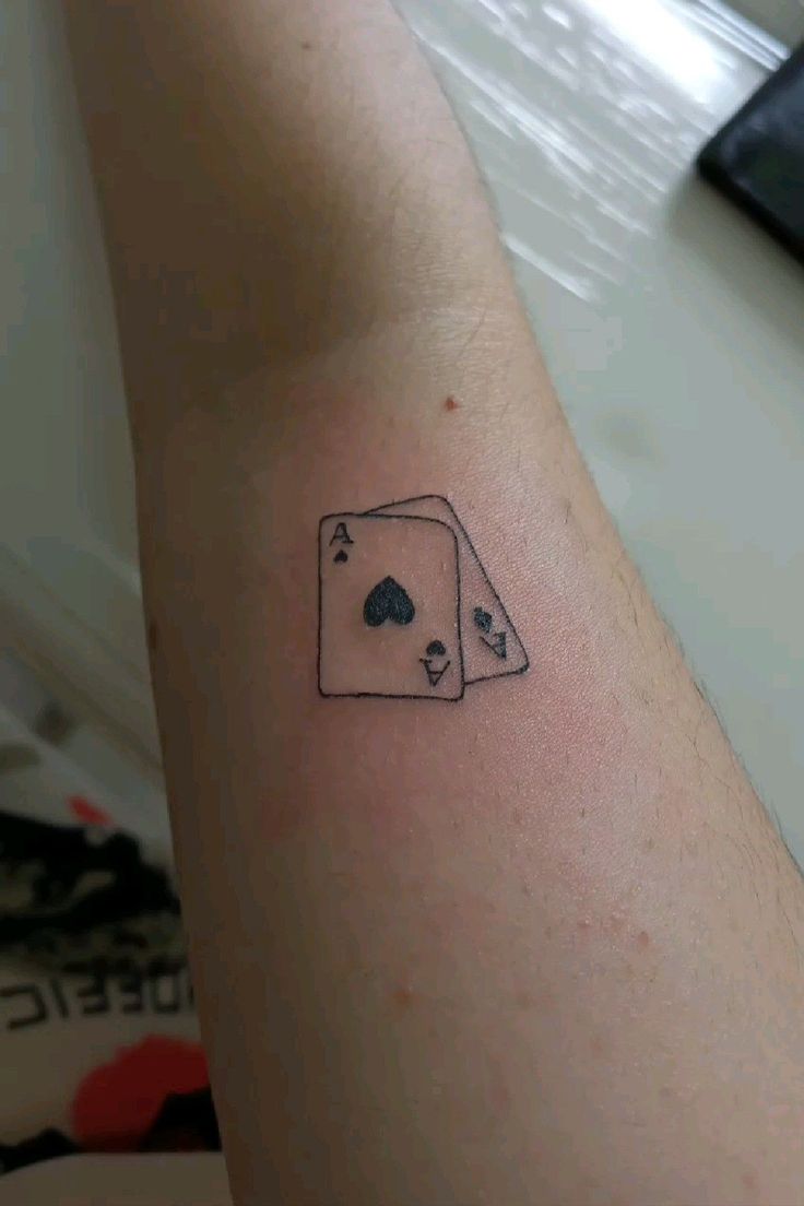 a person with a tattoo on their arm that has playing cards in the shape of dices